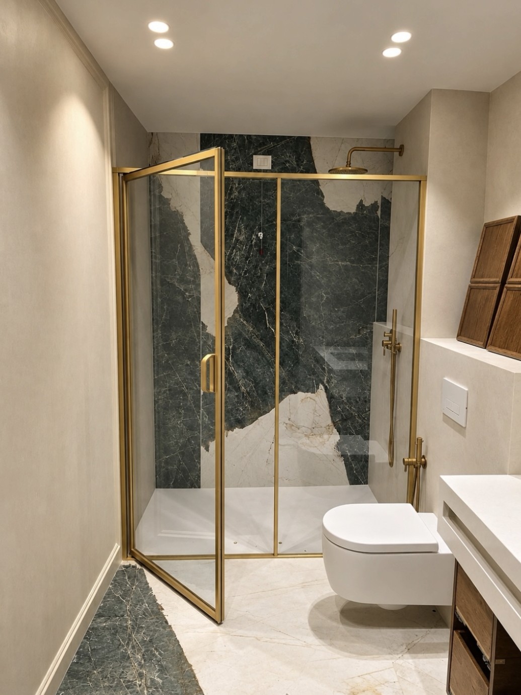 Shower door with warm metal profiles beside green stone