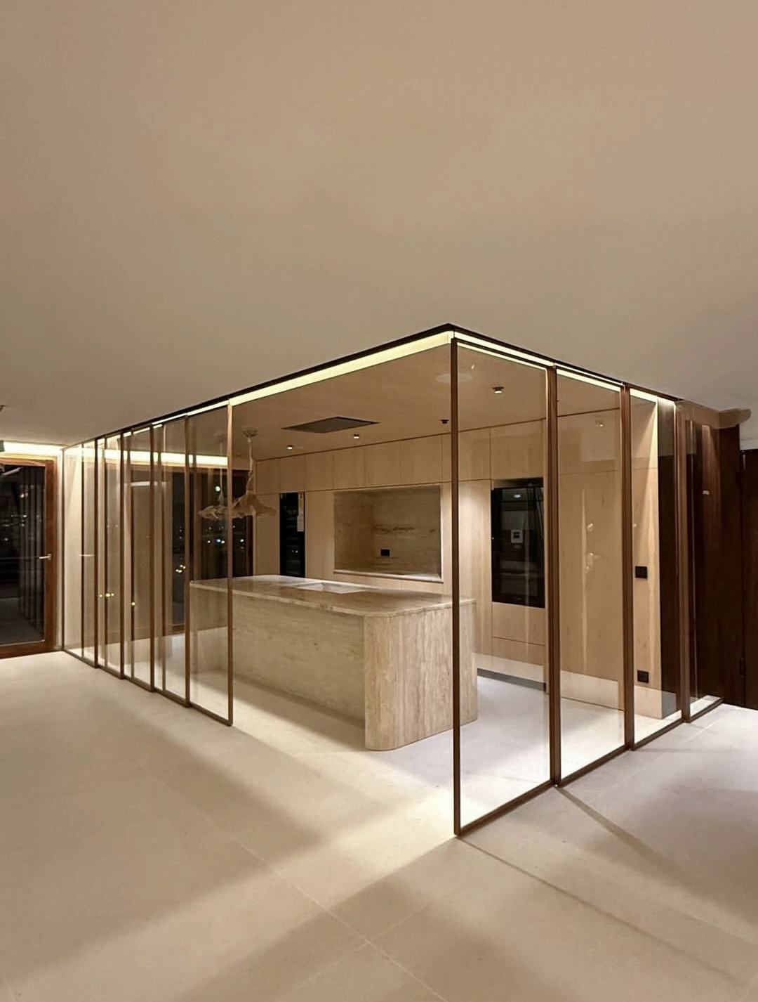 Glass enclosure around a kitchen with warm metal profiles